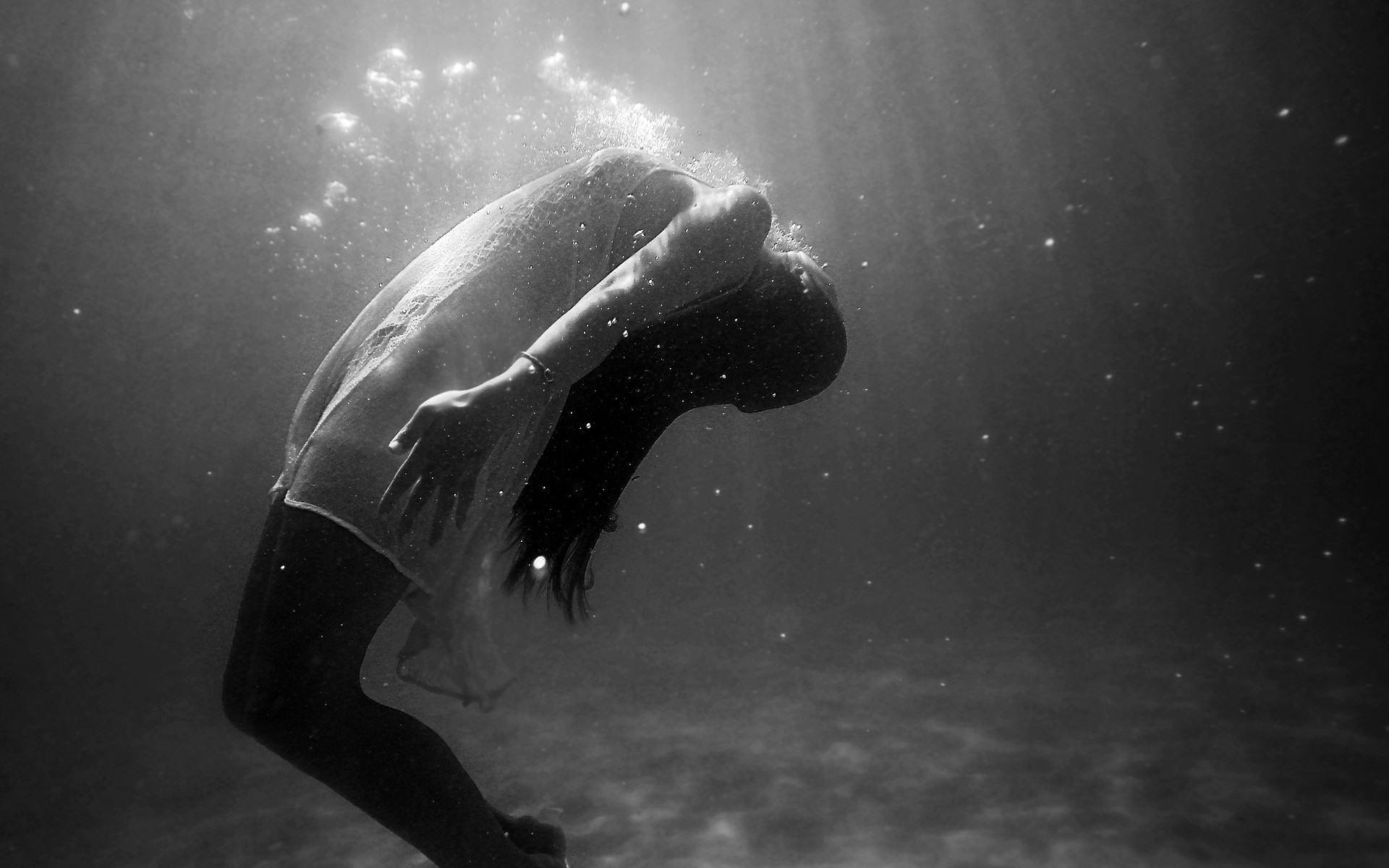 Image: Black and white photograph of a woman submerged beneath water.