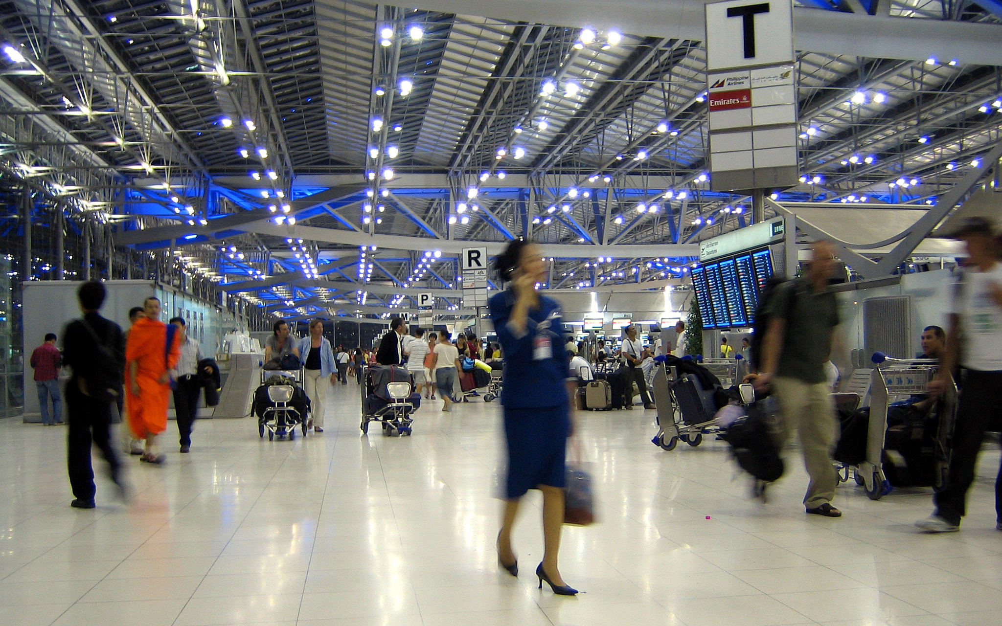 Image: People blurred and moving through a busy airport in Bangkok.
