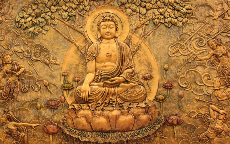 Image: A golden etching of the Buddha.