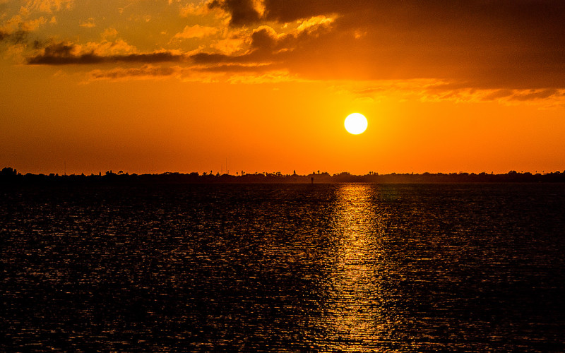 Image: The sun setting over a body of water.