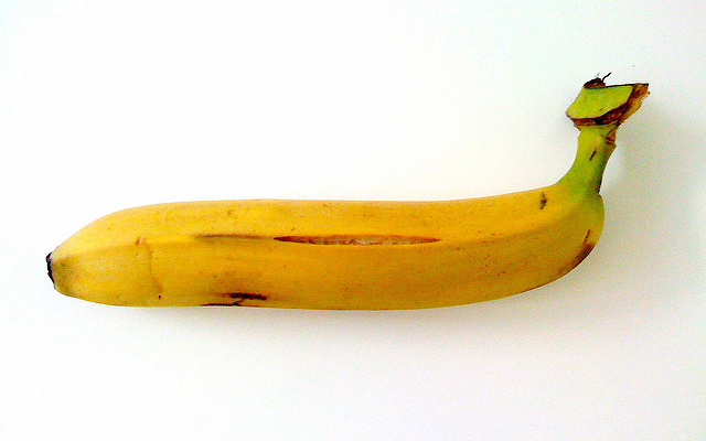 Image: A banana, skin slightly bruised and cracked.