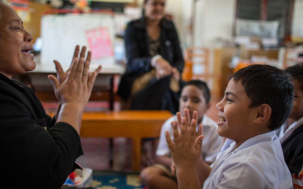 Image: A teacher clapping with a young student.