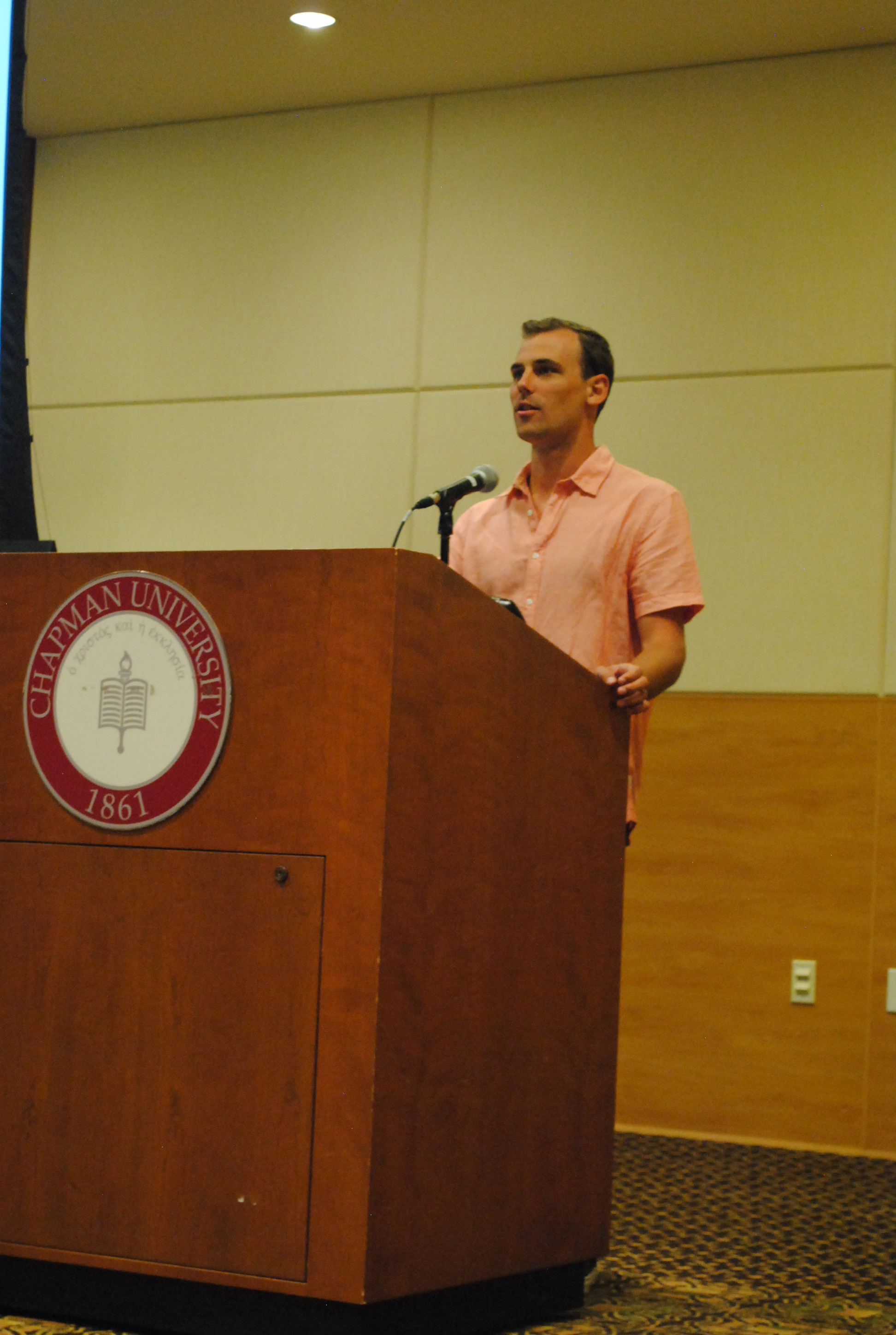 Image: Matt Wheatley speaking at a Chapman University podium.