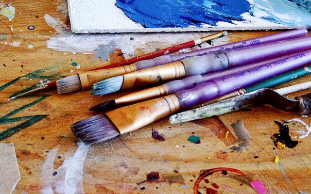 Image: Purple paintbrushes on an artist desk.