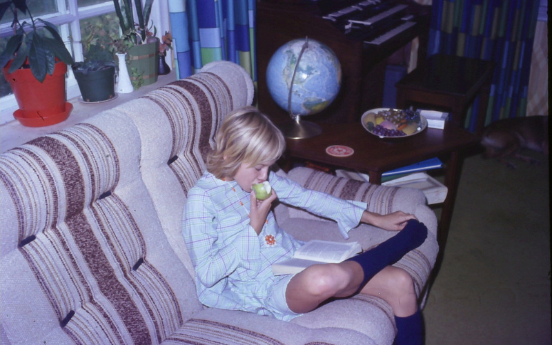 Image: A picture of a young person eating an apple and reading a book.