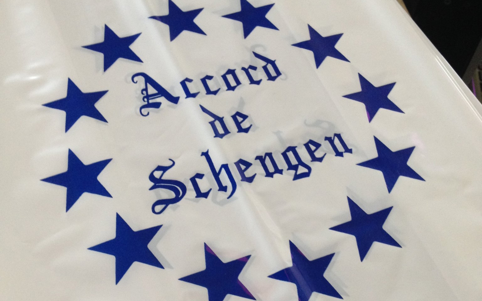 Image: A plastic sheet with "Accord de Schengen" written in calligraphy surrounded by blue stars